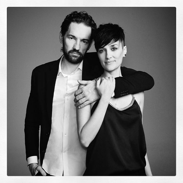 Nash Edgerton in a formal dress with his wife in a black sleeveless.